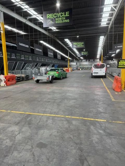 A car towing a trailer and a van driving into the hall